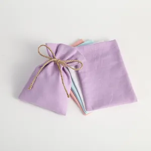 Multiple pastel cotton drawstring bags with natural jute twine closure shown in detail