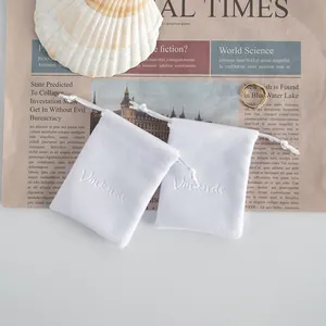 Primo piano dettagliato di morbidi sacchetti per gioielli in peluche bianco su giornale vintage