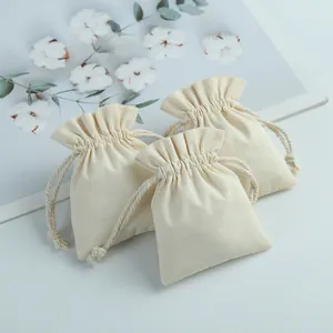 Detailed view of three small cream-colored cotton drawstring pouches for jewelry storage