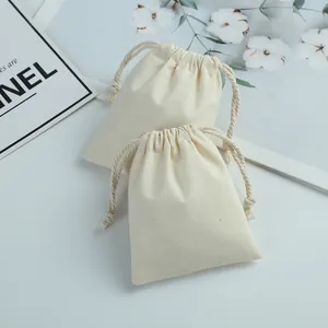Gros plan de deux pochettes en coton beige avec cordon de serrage sur fond blanc.