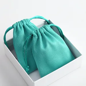 Primer plano de bolsas de gamuza turquesa para joyas con cordón en caja de regalo