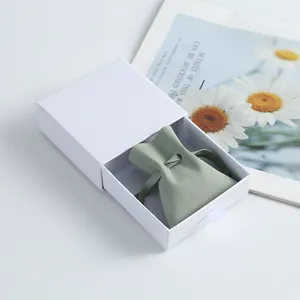 Nahaufnahme eines salbeigrünen Mikrofaserbeutels in einer weißen Schmuckschubladenbox.