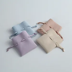 Set of four pastel microfiber jewelry pouches with drawstring closure on gray background.