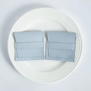 Vista detallada de dos bolsitas de microfibra azul claro para joyas sobre plato blanco