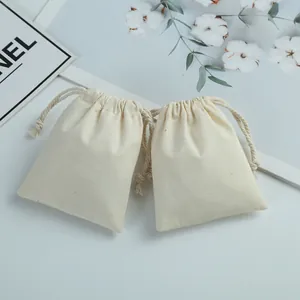 Détail de deux petits sacs à cordon en coton crème pour l'emballage de bijoux cadeau