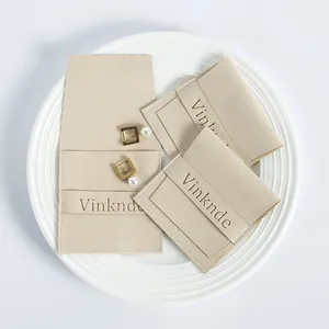 Bolsa de microfibra beige para joyas con cierre de solapa y detalle de logo en relieve