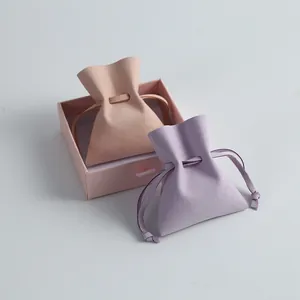Close-up of two colorful microfiber drawstring jewelry pouches with a pink gift box.