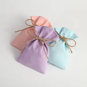 Set of small fabric drawstring pouches in pastel pink, purple, and blue with twine bows