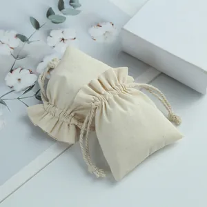 Close-up of cream cotton drawstring pouches with ruffled tops for jewelry storage