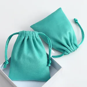 Detalle de cerca de bolsas de gamuza turquesa para joyas con una caja de regalo blanca.