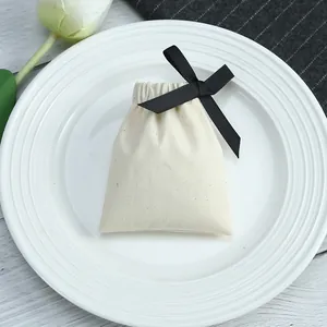 Gros plan d'une pochette cadeau en coton crème avec un élégant nœud en ruban noir