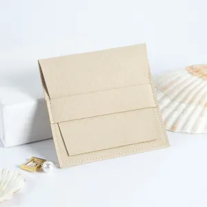 Vista detallada de una bolsa para joyas de microfibra beige con cierre de solapa