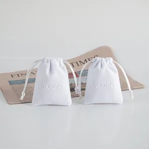 Vista dettagliata di un sacchetto per gioielli in velluto bianco con logo goffrato