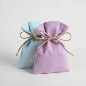 Close-up of light blue and lavender canvas drawstring gift bags with jute twine bow