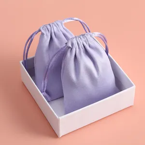 Detalle de dos suaves bolsitas de terciopelo lavanda en una caja de regalo blanca.