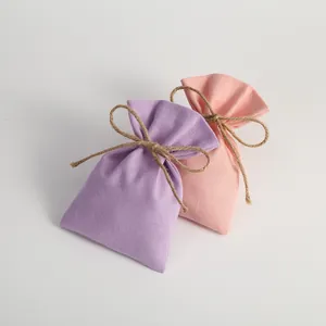 Detailed view of colorful canvas drawstring gift pouches with rustic jute twine bows