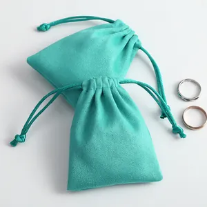 Primer plano detallado de bolsas de joyería de gamuza microfibra turquesa con dos anillos.