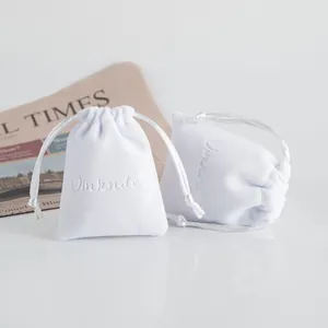Primo piano di eleganti sacchetti in velluto bianco con coulisse per gioielli e regali
