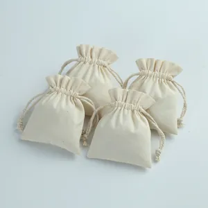 Detail view of four cream cotton drawstring pouches for jewelry packaging and storage