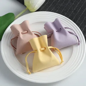 Soft microfiber drawstring jewelry pouches in pastel pink yellow and purple on white plate