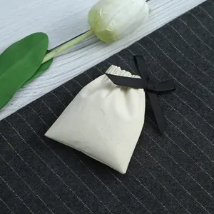 Détail d'une pochette à bijoux en coton crème avec un nœud en ruban gros-grain noir