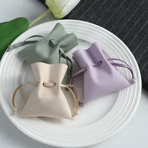 Detail view of microfiber drawstring jewelry pouches in green, purple, and beige