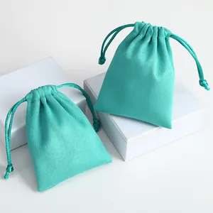 Detalle de bolsas de gamuza turquesa para joyas con cordón sobre cajas blancas