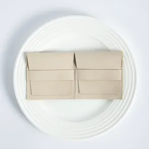 Detalle de bolsitas de microfibra beige para joyas con solapa y tira en plato blanco