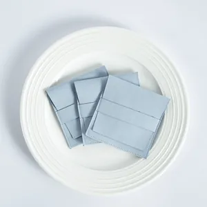 Detalle de tres bolsas de microfibra para joyas azul claro sobre un plato blanco