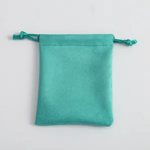 Detalle de la bolsa de gamuza con cordón en color verde azulado y textura de costura