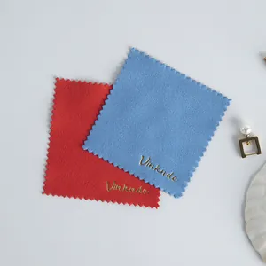 Detail view of two soft microfiber cleaning cloths with gold brand logo for jewelry