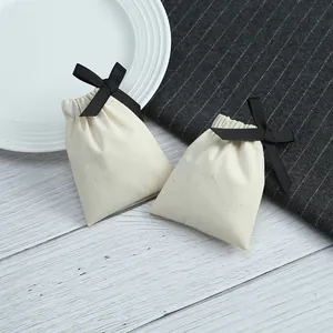 Détail de petites pochettes à bijoux en coton crème avec un nœud papillon noir élégant