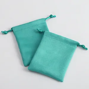 Detalle de dos bolsas de microfibra color turquesa con cordón para joyería.