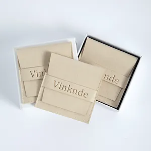 Vista detallada de bolsas de joyería de microfibra de gamuza beige con logotipo grabado