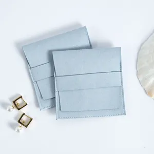 Primer plano de bolsas de joyería de microfibra de ante azul claro con solapa y correa