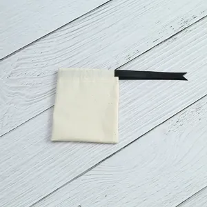Vue détaillée d'un pochon en coton crème avec poignée en ruban noir
