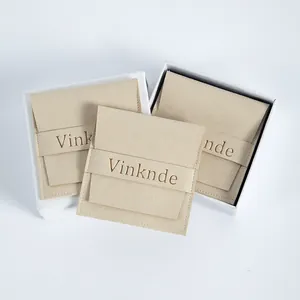Vista detallada de bolsas de joyería en microfibra beige con logo y cajas de regalo