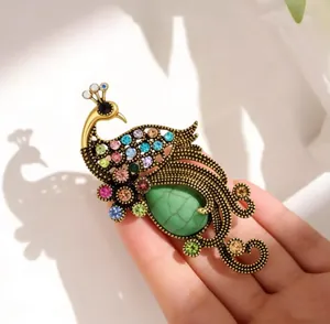 Detailed close-up of a vintage peacock brooch with colorful rhinestones and green stone
