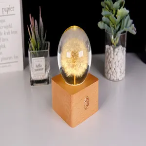 Detailansicht eines kreativen Pusteblumen-Kristallkugel-Nachtlichts auf einem warmen Holzsockel