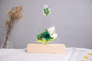 Détail de rose éternelle verte et de fleurs blanches sur un socle de veilleuse LED