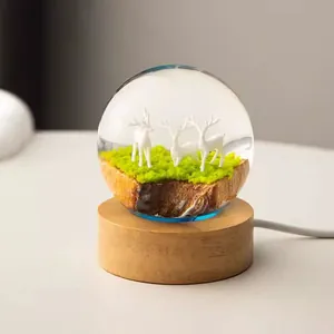 Close-up of a decorative crystal ball night light with deer scene on a wooden base