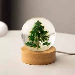 Detail of crystal ball night light featuring a Christmas tree and white deer inside.