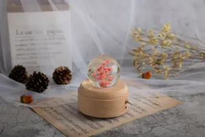 Elegante Kristallkugel-Spieluhr mit rosa Ewigkeitsblumen auf rundem Holzsockel