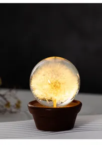 Close-up of dandelion crystal ball night light with a warm glow and walnut wood base.