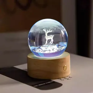Close-up of a glowing crystal ball night light with 3D elk on a natural wooden base