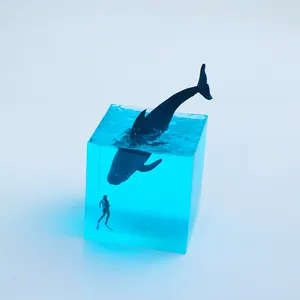 Close-up of a micro landscape ocean resin cube featuring a whale and miniature diver.
