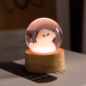 Warm glow crystal ball night light featuring cute fluffy dog on natural wooden base