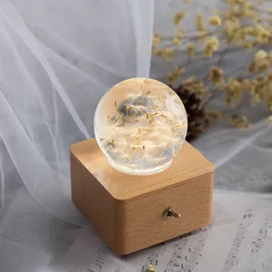 Detail einer romantischen Löwenzahn-Kristallkugel-Spieluhr mit einem Holzsockel.