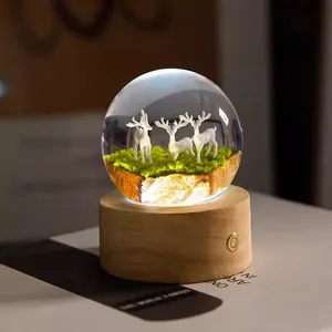 Detailed view of a glowing crystal ball night light featuring deer on a wooden base.