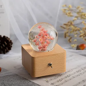 Spieluhr Kristallkugel mit rosa Trockenblumen auf quadratischem Holzsockel